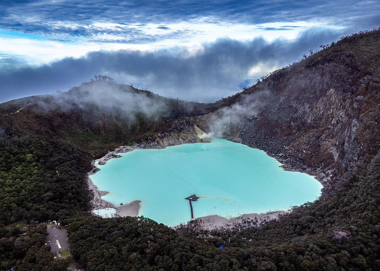 Aerial drone view of Kawah Putih crater lake, showing the turquoise sulfur pool, Ponton floating pier, and Mount Patuha caldera walls