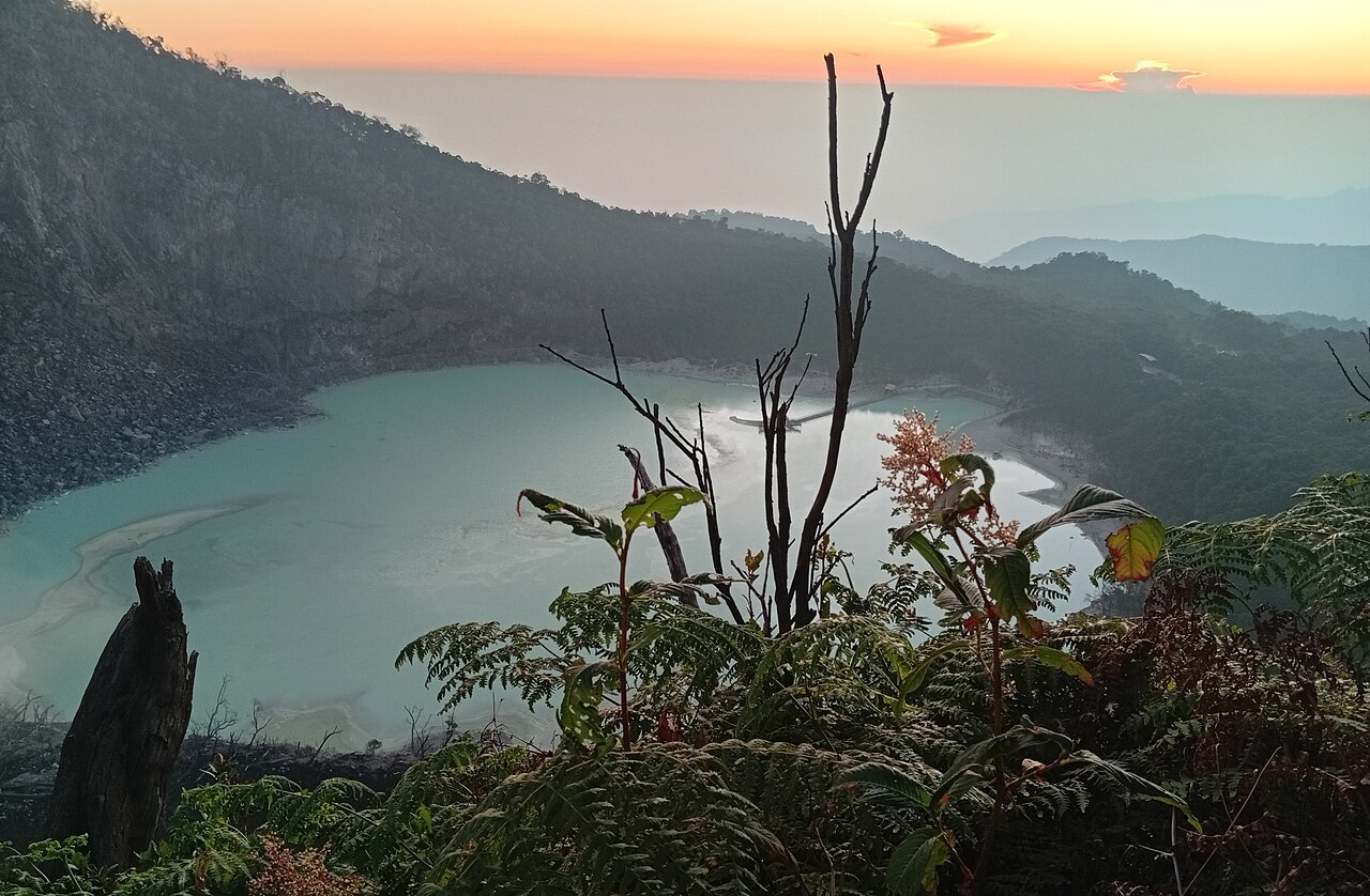 Spectacular sunrise panorama looking down on Kawah Putih crater lake from Puncak Sunan Ibu viewpoint at dawn