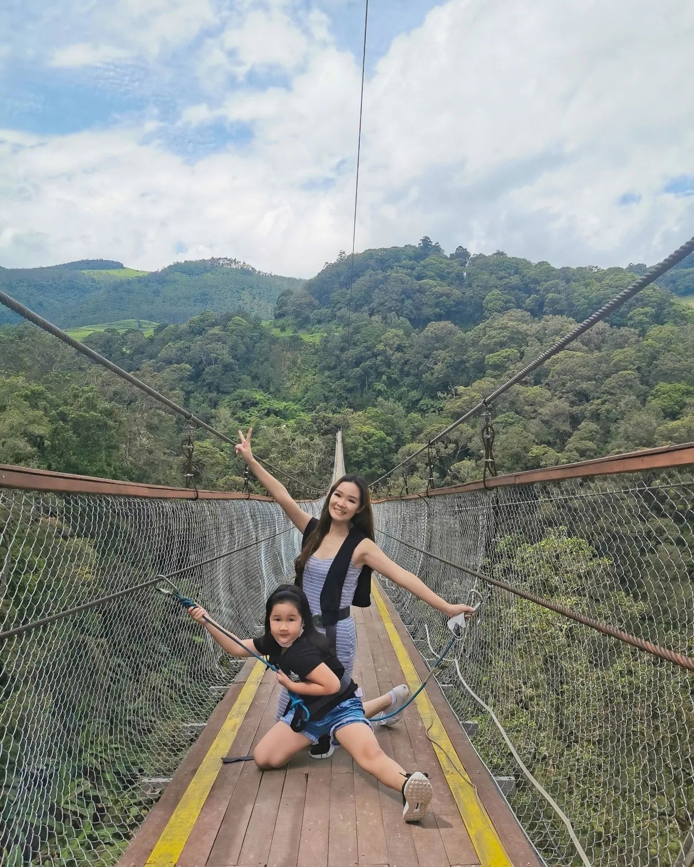 Visitors walking along the 370-meter wooden deck of Rengganis Suspension Bridge high above the canyon in Ciwidey