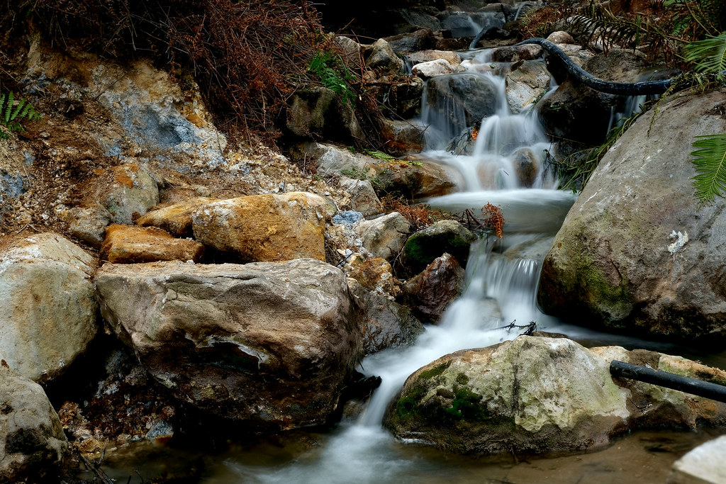 Gentle natural volcanic hot spring stream cascading over thermal mineral rocks at Kawah Rengganis Ciwidey