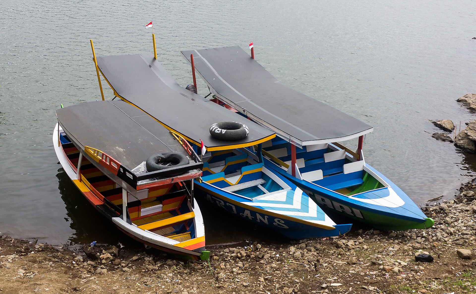 Fleet of colorful traditional wooden motorboats moored along the shore of Situ Patenggang lake in Bandung Regency